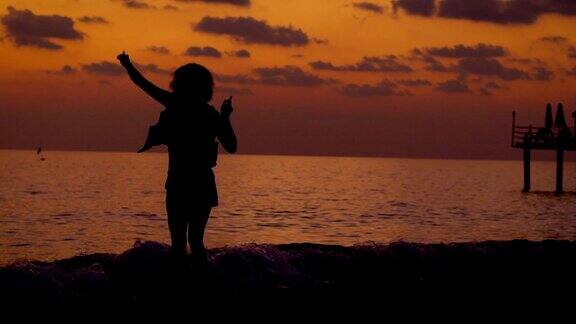 日落时美丽的年轻女孩在海滩上