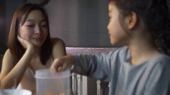 一个美丽的亚洲母亲和她的女儿做饭一对家庭夫妇准备牛奶和麦片粥作为早餐