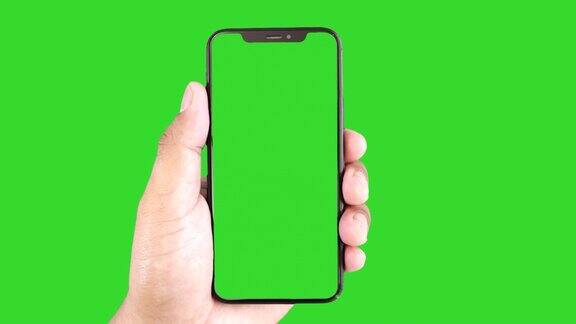 男士手持绿色屏幕的黑色智能手机触摸或按下显示男士使用绿色背景的色度键触摸手机