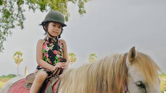 小女孩骑着马在乡村的路上