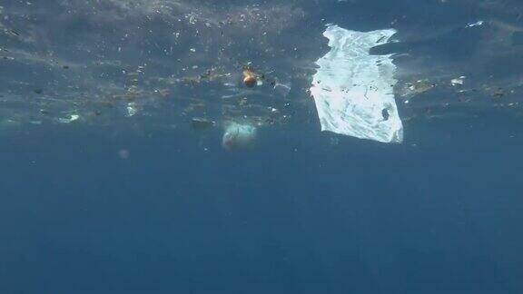 塑料和其他垃圾慢慢漂浮在蓝色的水面上接近珊瑚礁大量污染海洋