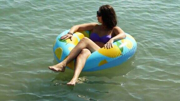 暑假里一个女人穿着比基尼躺在装满柠檬的充气床垫上在海里游泳俯视图的一个女孩放松日光浴享受旅行