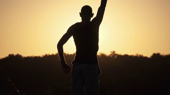 夕阳下举起双手的人的剪影自由慢动作