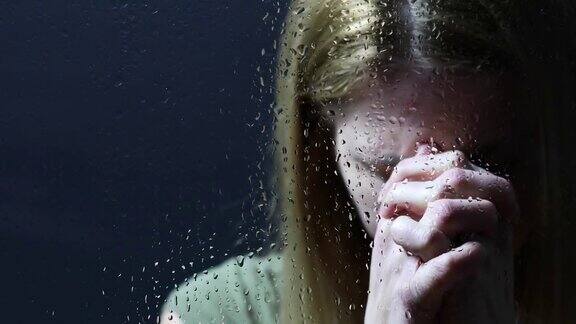 透过湿窗祈祷的女人