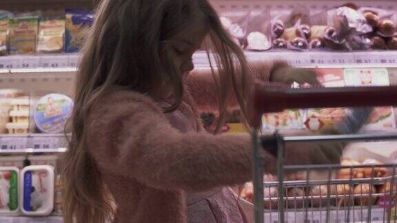 小女孩把香肠放进超市的购物车里