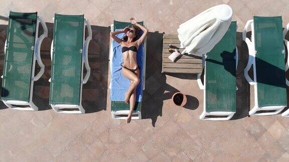 无人机拍摄的一个女人在游泳池旁边晒太阳
