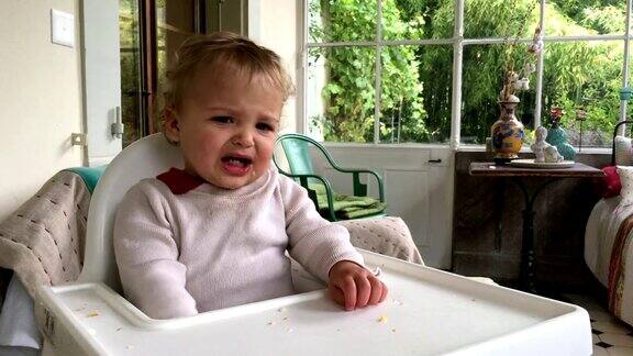 一岁的婴儿在高脚椅上哭金发小男孩在等食物的时候哭着