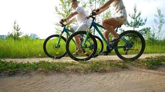年轻快乐的夫妇在夏天的田野小径上骑车