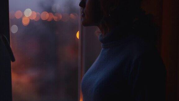 傍晚的街道上透过窗户望出去的女人