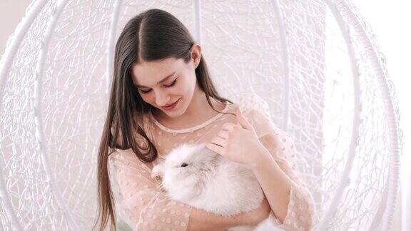 可爱的女孩抱着兔子揉着它