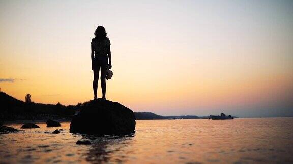 年轻女子看着海上的日落