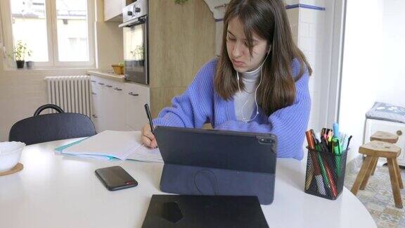 十几岁的女孩在网上上课在家使用笔记本电脑和入耳式耳机