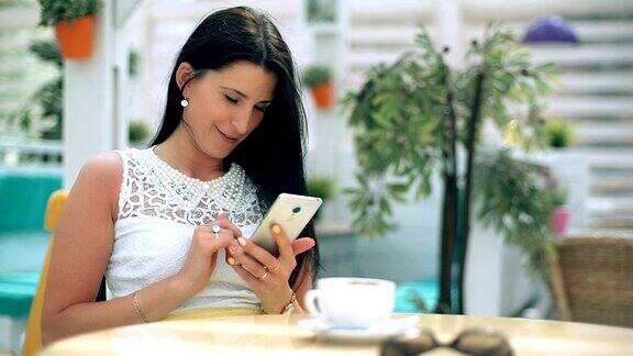 年轻女子在咖啡馆用智能手机打字
