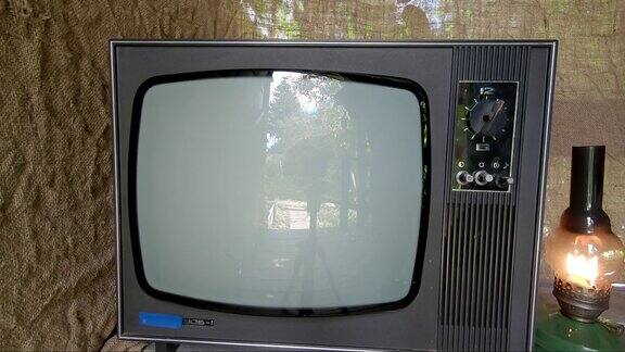 一个拿着煤油灯的男人打开了一台老式的电视