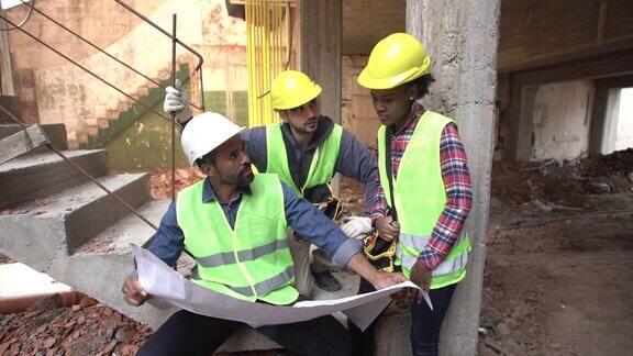 图为建筑工人在施工现场讨论图纸
