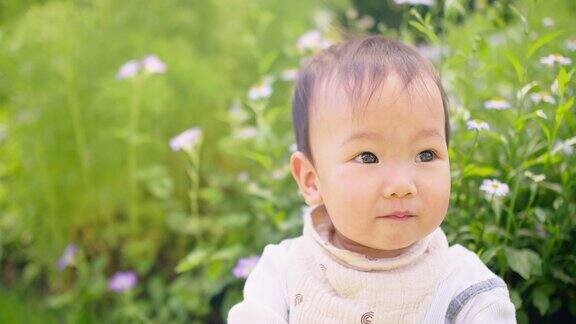 可爱的亚洲小婴儿蹒跚学步的女孩在家门口的花园微笑着看着相机
