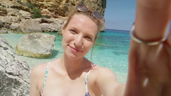 美丽的女人在海滩上用智能手机视频聊天自拍微笑享受热带自然背景暑假旅行冒险POV