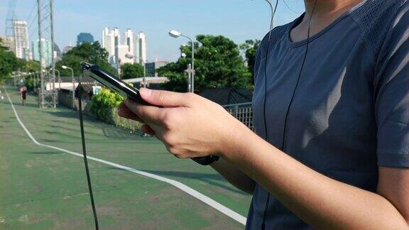 亚洲女运动员在跑步后用智能手机检查心率日落时分在街上慢跑锻炼的生活方式健康的生活方式