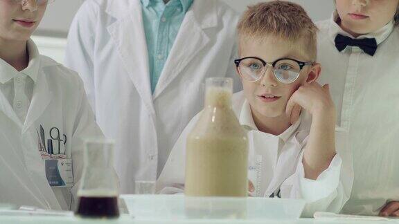 好奇的男孩在做科学实验实验室内部沸腾的泡沫液体近距离