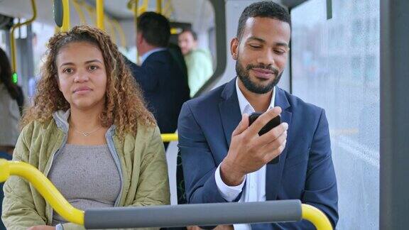在公交车上一个男人坐在一个女人旁边进行视频通话