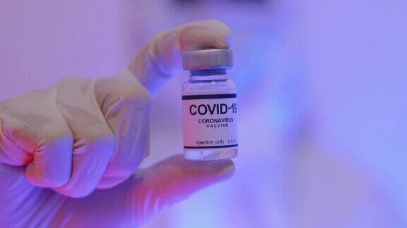 亚洲医生手持并展示Covid-19疫苗瓶
