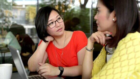 年轻的亚洲女性在咖啡馆使用笔记本电脑