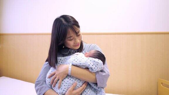 年轻的母亲抱着她刚出生的婴儿在医院里