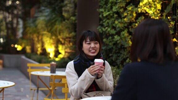 年轻女性朋友在户外咖啡馆聊天-2部分的第一部分