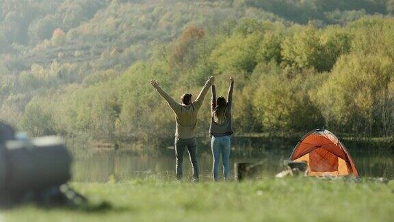 男人和女人走到湖边举起双手