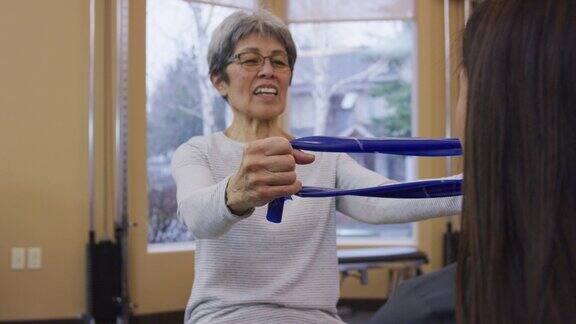 在物理治疗会议上使用阻力带的老年妇女