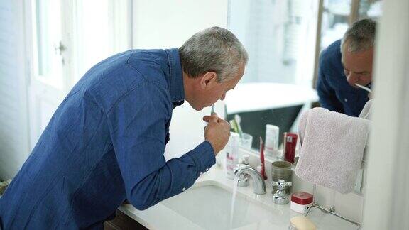 一个老人在浴室里刷牙