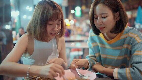 两个快乐的女人享受着第一次吃街头小吃
