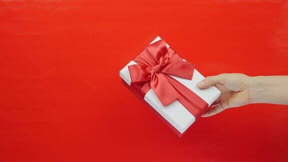 手显示白色盒子与红色丝带蝴蝶结在红色的背景女性手里拿着情人节礼物情人节国际妇女节
