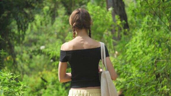 在阳光明媚的日子里女士沿着绿色的森林景观散步