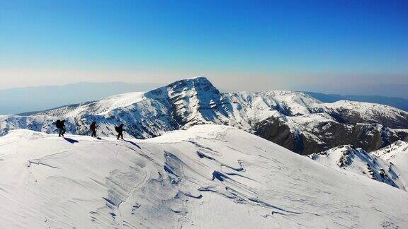 无人机拍摄成功的登山队伍在冬季在高海拔雪山峰顶的山脊上排排攀登