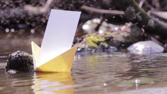 黄色的纸船漂浮在池塘的浑水上