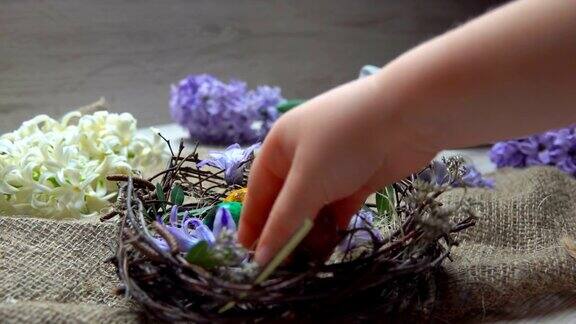 孩子的手在复活节的巢里产下有颜色的蛋