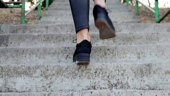 特写女性的腿在黑鞋爬楼梯慢动作低角度拍摄