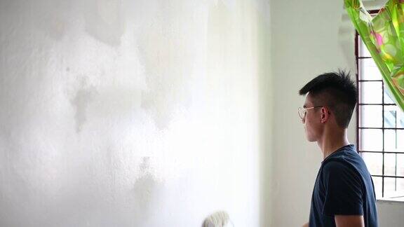 日落时分一名亚裔中国男孩正在粉刷自己的卧室和公寓