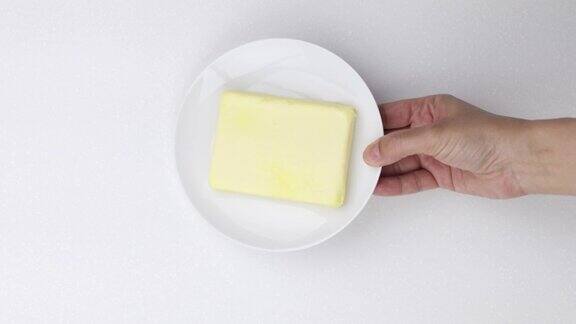 手把一块黄油放在盘子上
