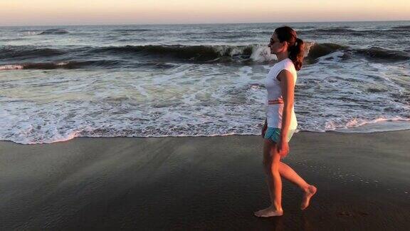 日落时分一名女子在海滩上散步