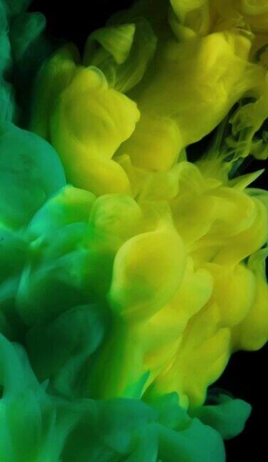 垂直抽象背景流动的丙烯酸油墨在水孤立的黑色背景慢动作的多色液体流动黄色和绿色的油墨缓慢运动和混合流入水中丙烯酸涂料在水中颜色在运动深的空间