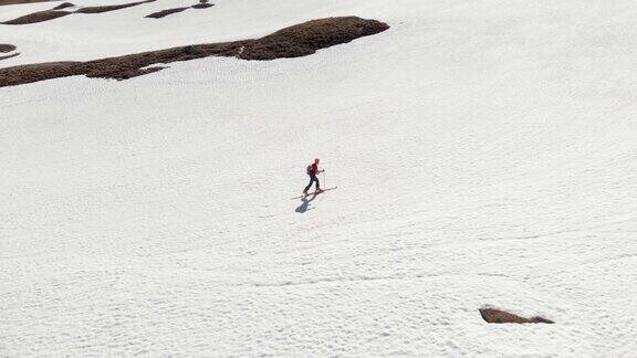 航拍:在雪山上行走的徒步者侧视图