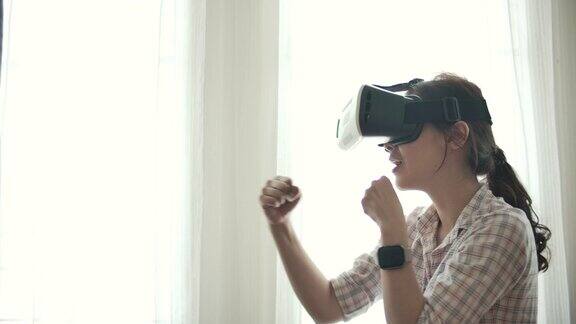 亚洲女性戴着VR眼镜在家玩游戏