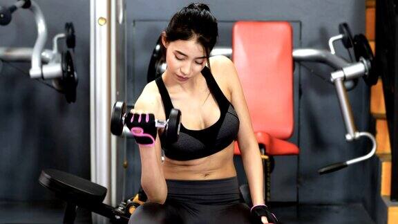 亚洲妇女锻炼举哑铃和在健身房抱心脏健康生活的理念与运动