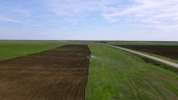 沿途的农田全景远处的拖拉机用专用设备犁耕耙地为季节性小麦播种准备土壤由无人机从高空拍摄