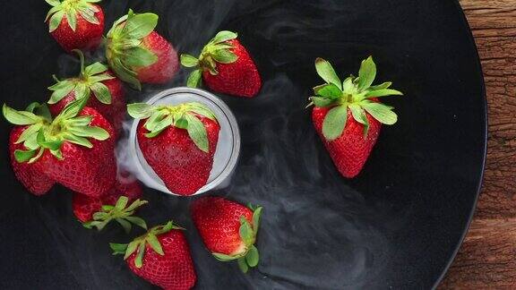 有机新鲜草莓冷冻在黑色的盘子顶视图草莓菜与冷烟