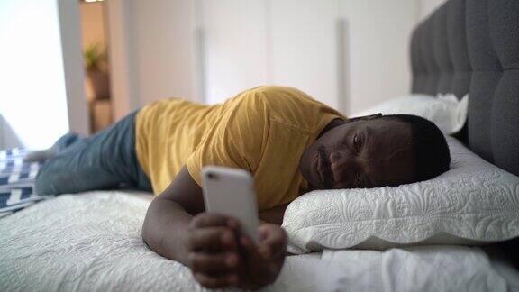 疲惫的老人躺在家里的床上使用智能手机