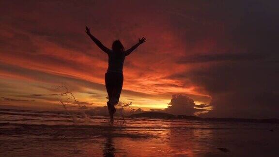 剪影:一个快乐的女人张开双臂奔向美丽的夕阳