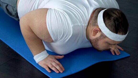 胖子摔倒在瑜伽垫上试图做平板支撑运动精力不足